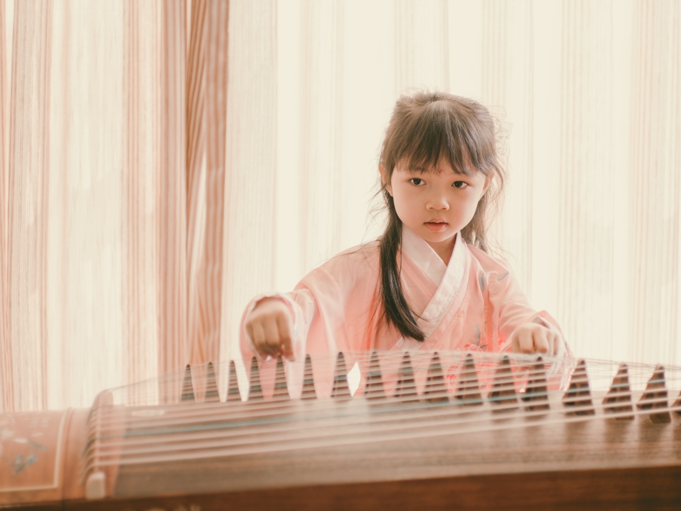 Маленькая девочка азиатка играет на музыкальном инструменте