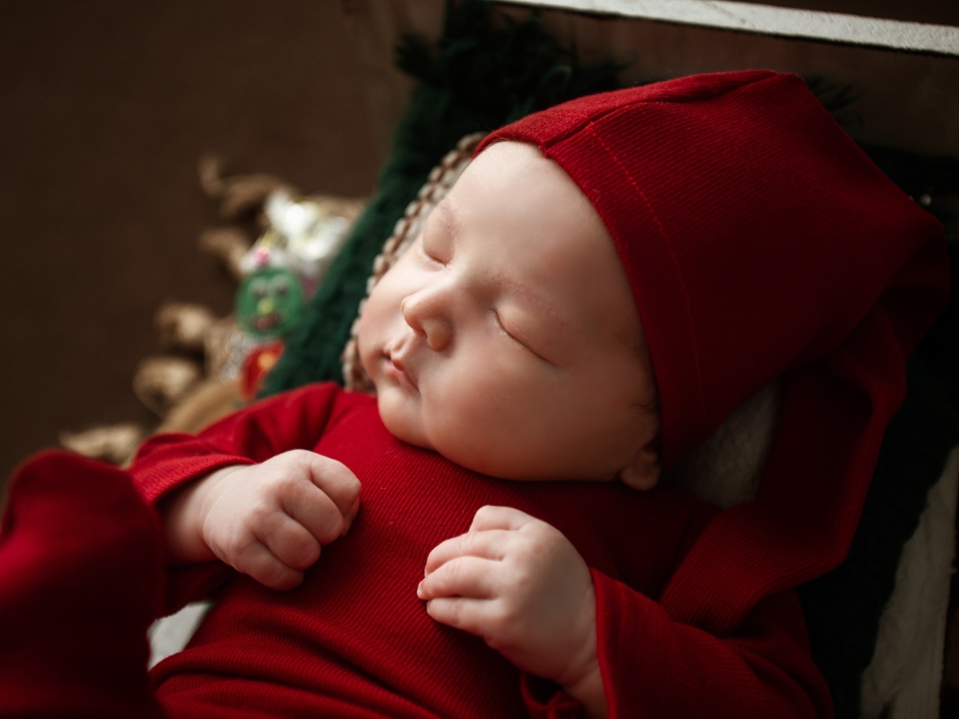 Маленький ребенок спит в красном костюме