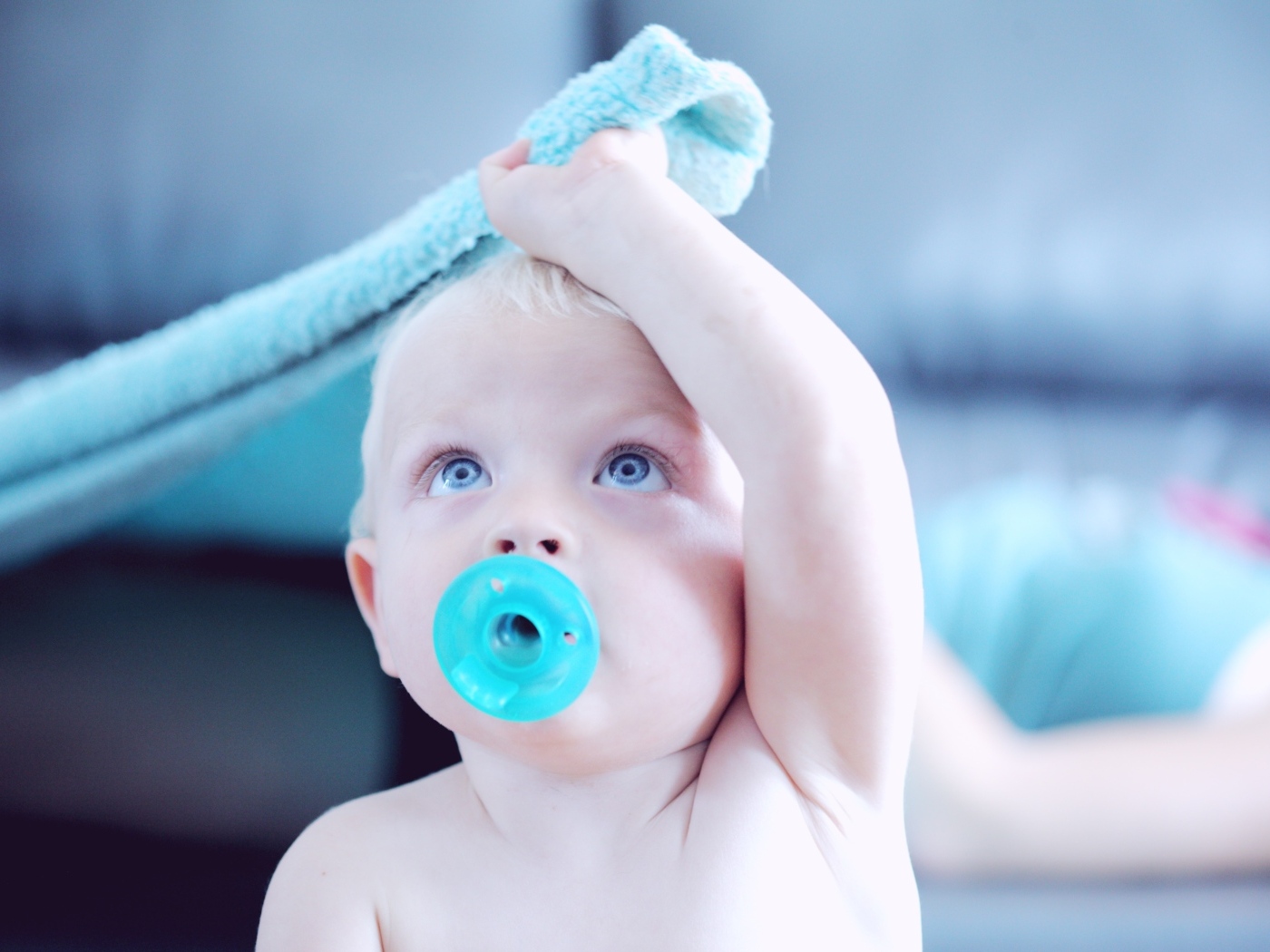 Маленький ребенок с голубой соской во рту