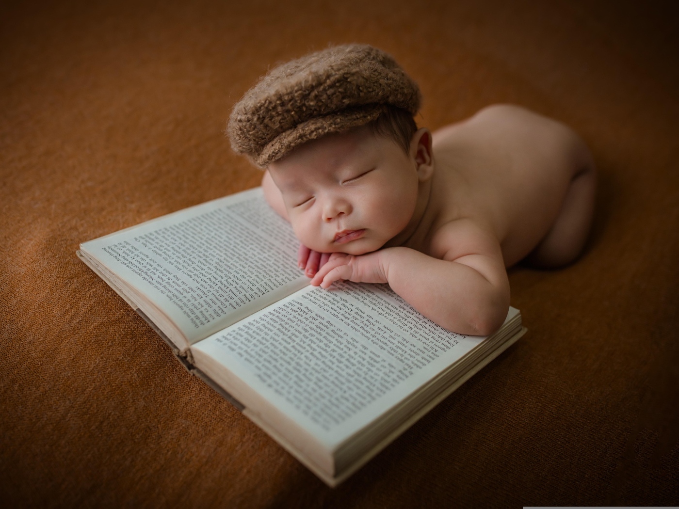 Новорожденный малыш спит на книге