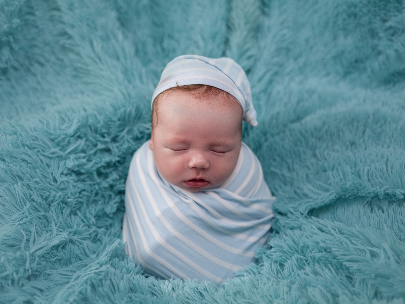 Спящий новорожденный малыш на голубом покрывале 