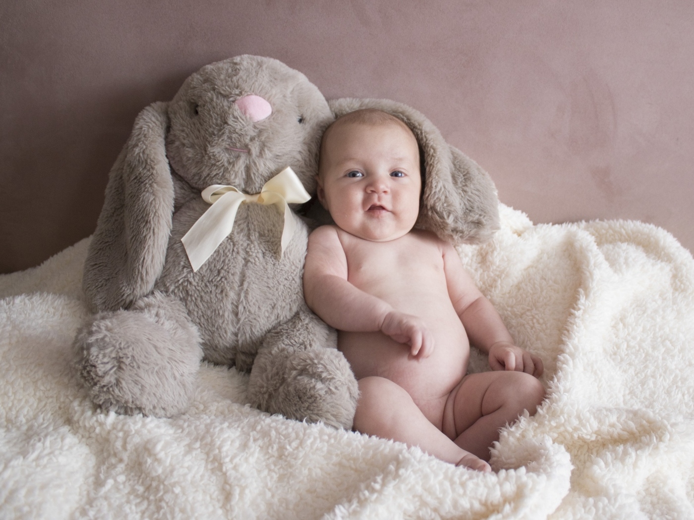 Улыбающийся малыш с игрушечным зайцем