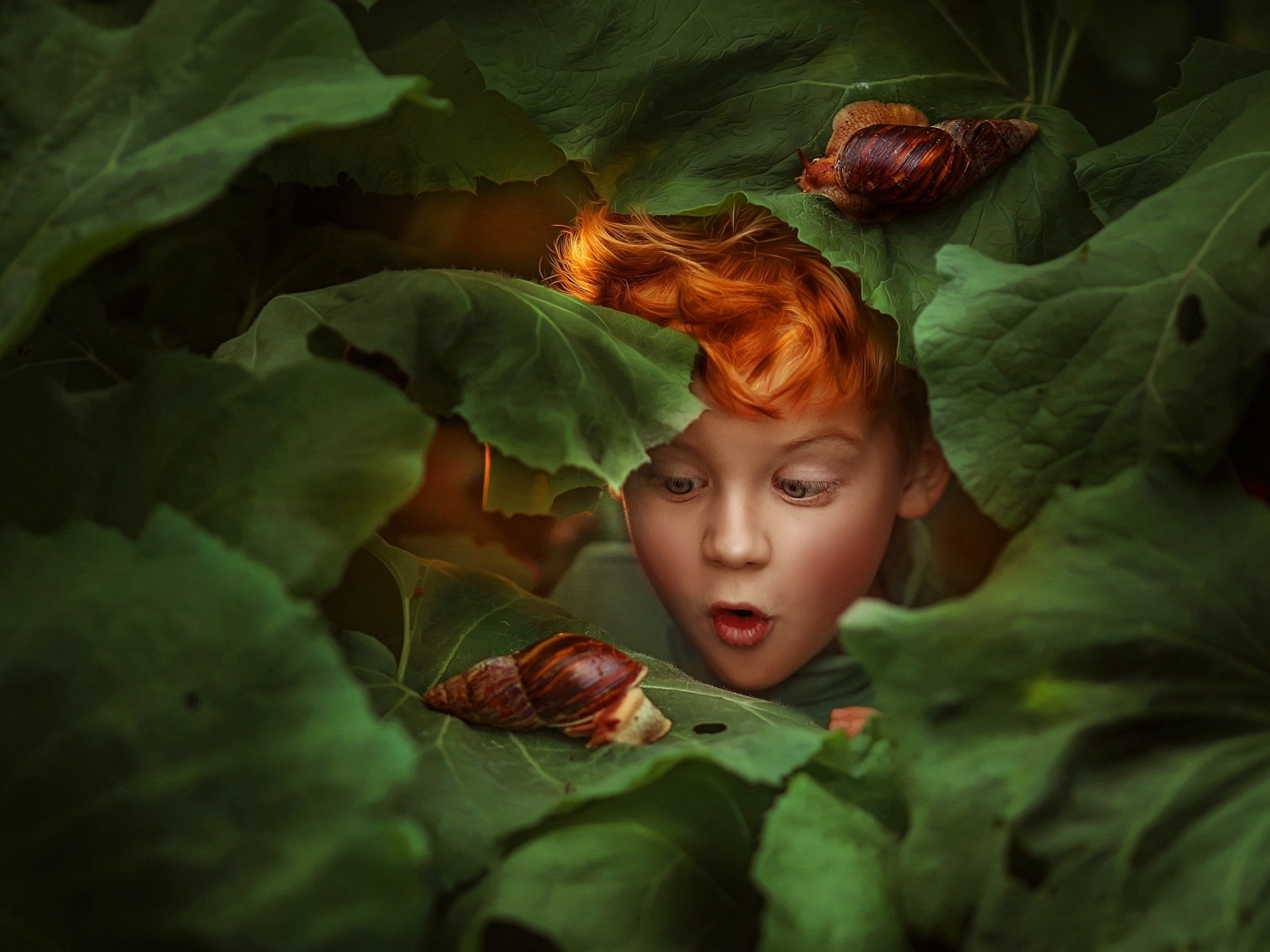 Удивленный рыжеволосый мальчик смотрит на улитку