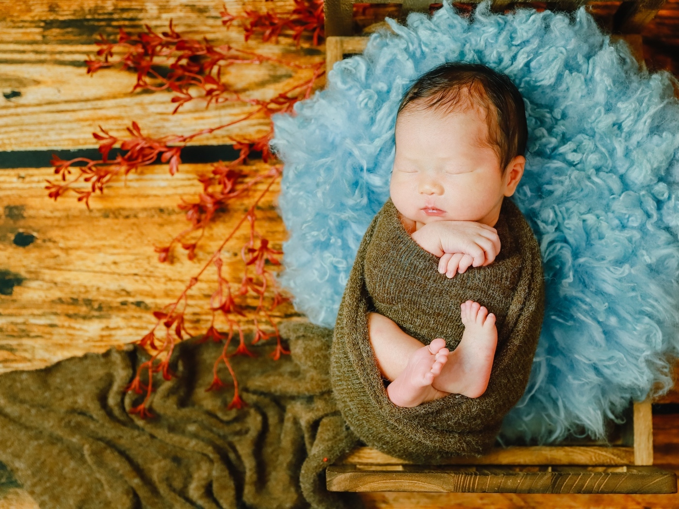 Крошечный новорожденный ребенок на голубой меховой подушке