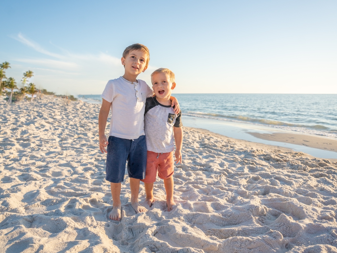 Два маленьких мальчика стоят на песке у моря
