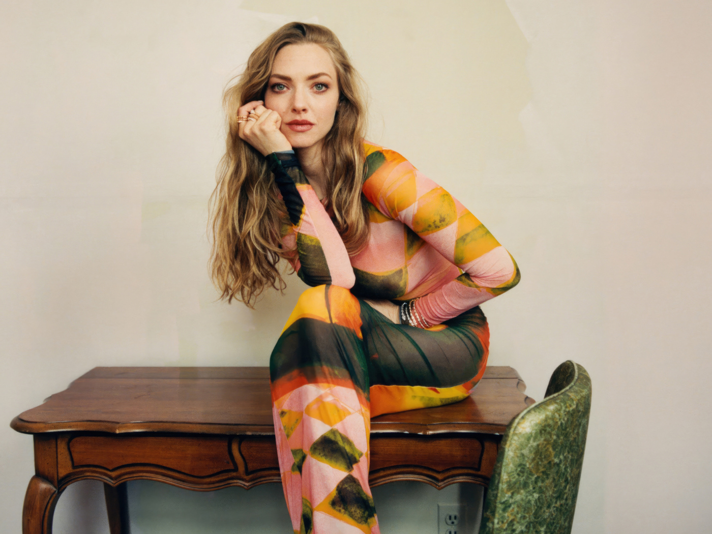 Актриса Аманда Сайфред в платье сидит на столе