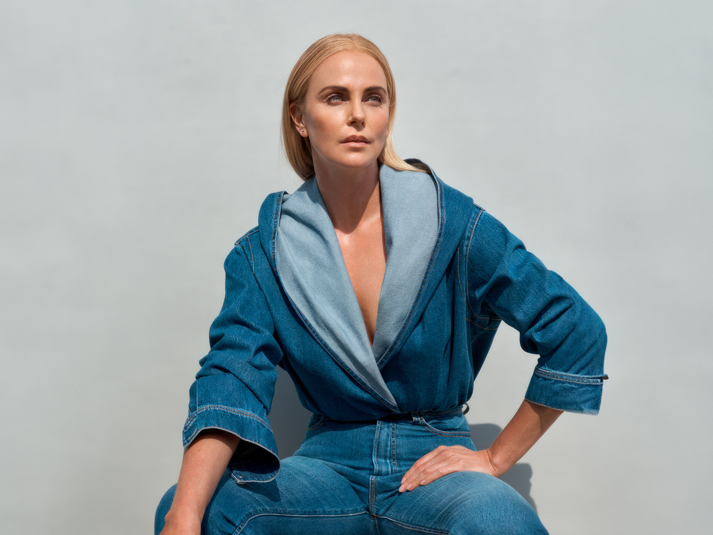 Актриса Шарлиз Терон в джинсовом костюме на сером фоне