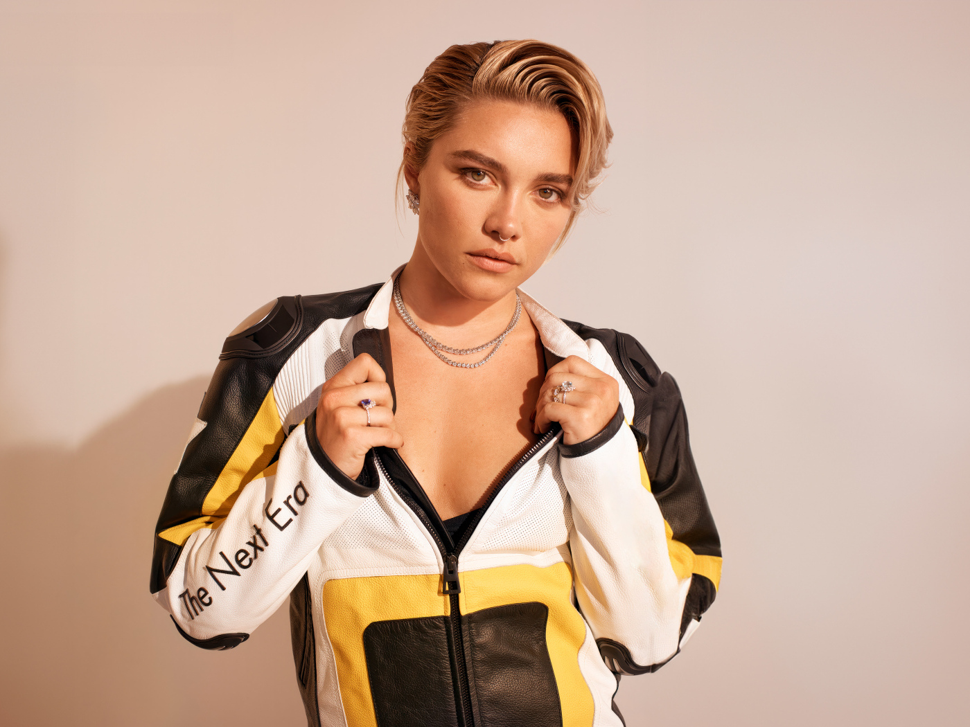 Актриса Флоренс Пью в спортивной куртке на розовом фоне