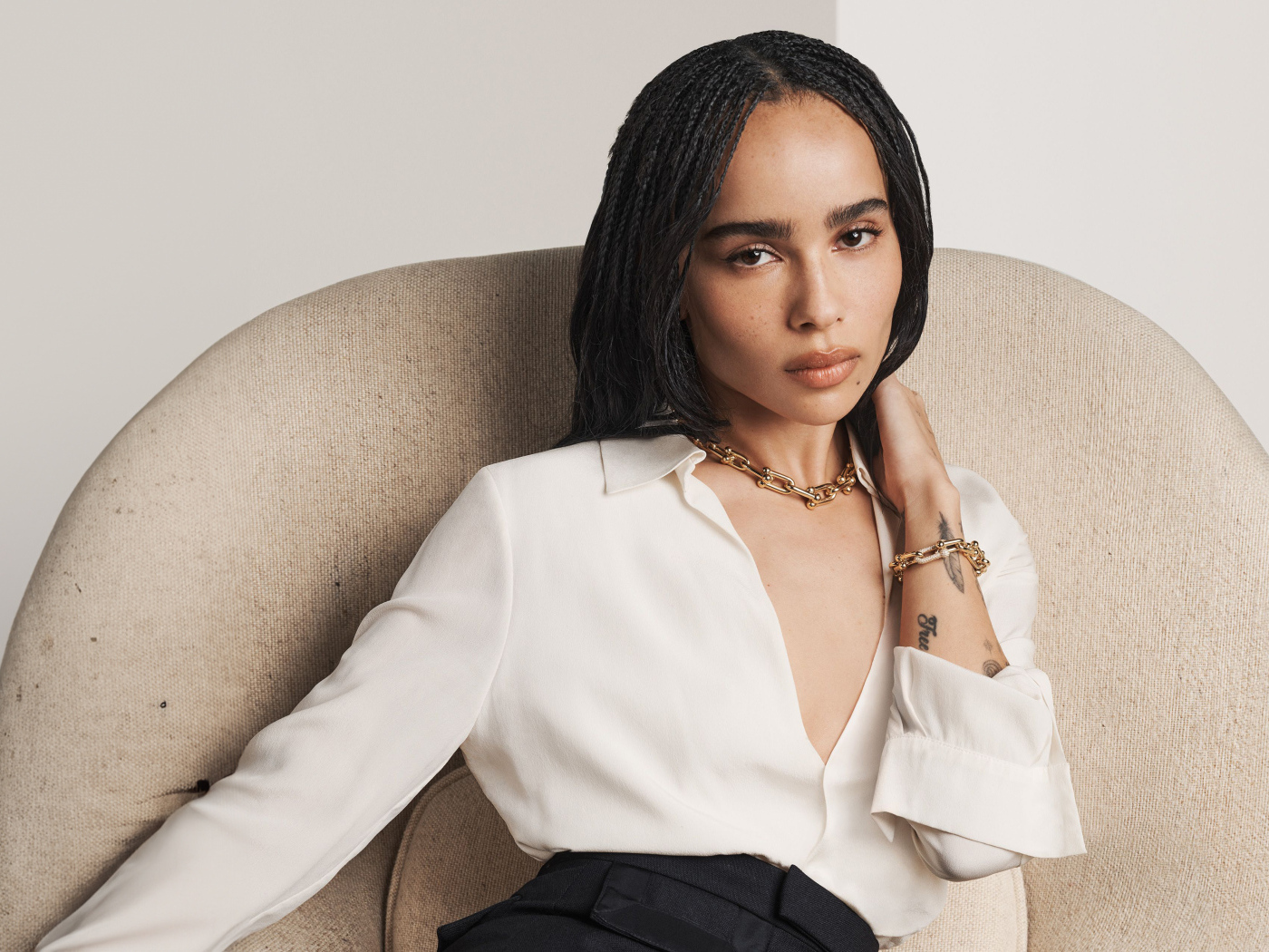 Актриса Зои Кравиц в белой рубашке сидит в кресле