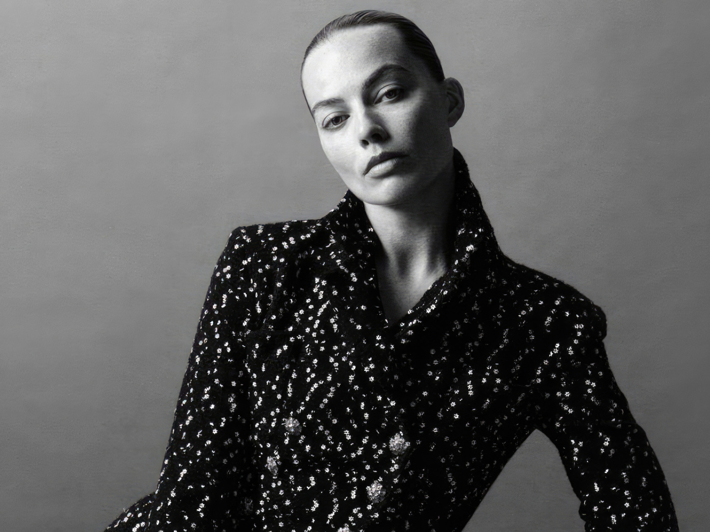 Грустная Марго Робби в блестящем пиджаке на сером фоне