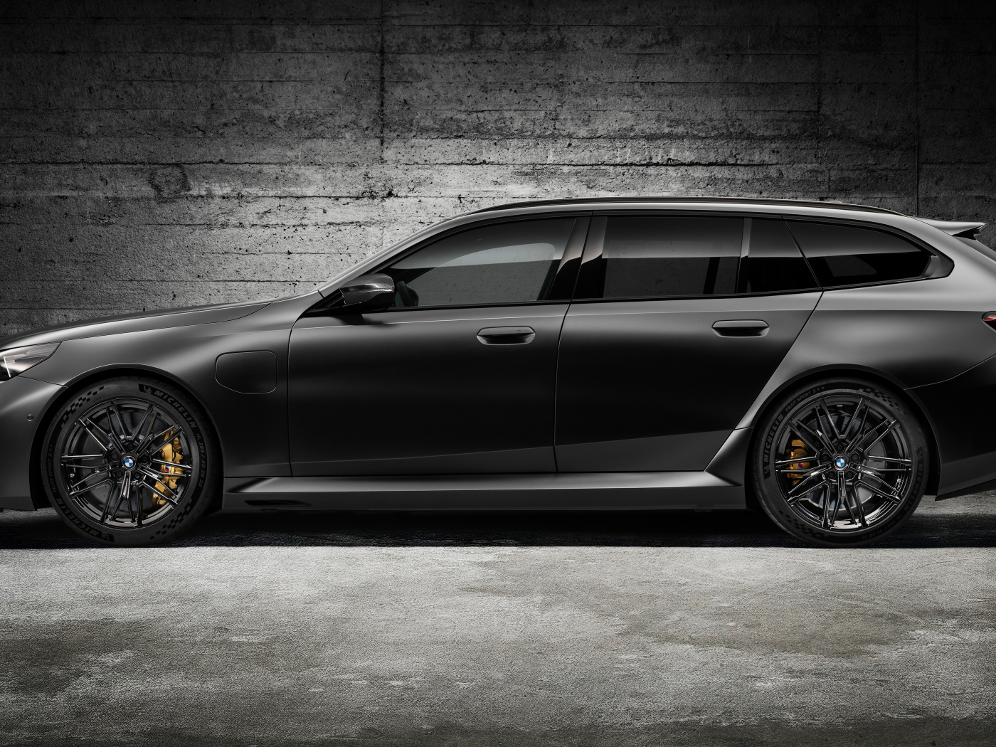 Вид сбоку на черный автомобиль BMW M5 Touring 2024 года