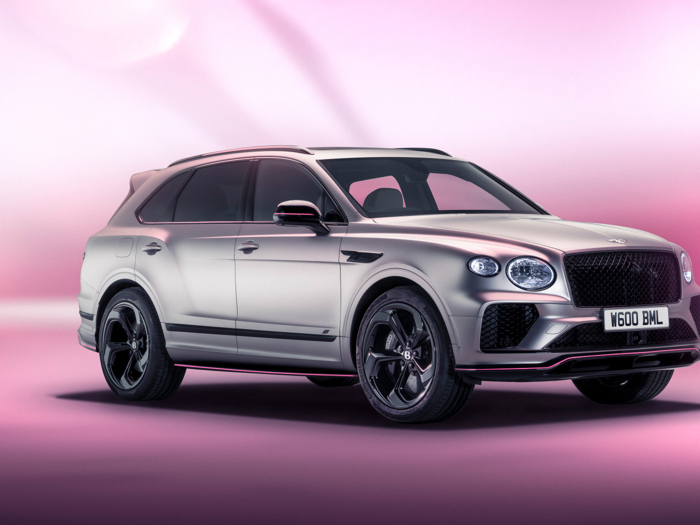 Серебристый автомобиль Bentley Bentayga V8 S Curated By Mulliner 2024 года на розовом фоне
