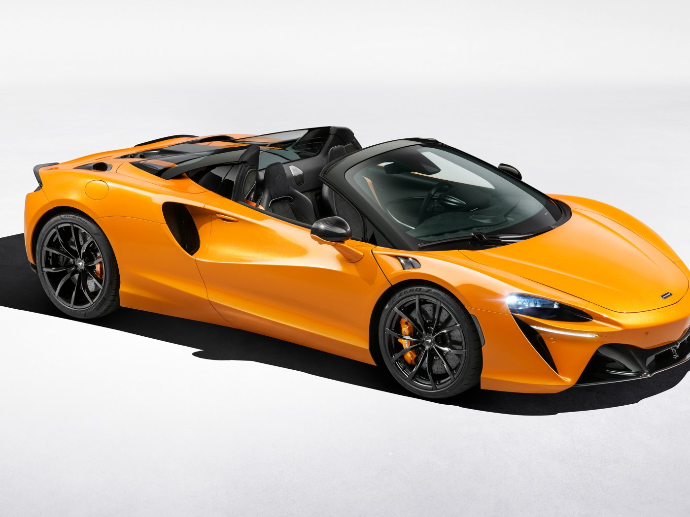 Оранжевый автомобиль McLaren Artura Spider на сером фоне