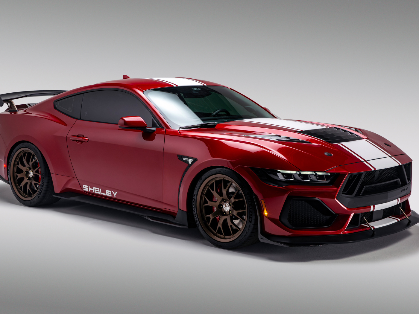 Красный автомобиль Shelby Super Snake 2024  года на сером фоне