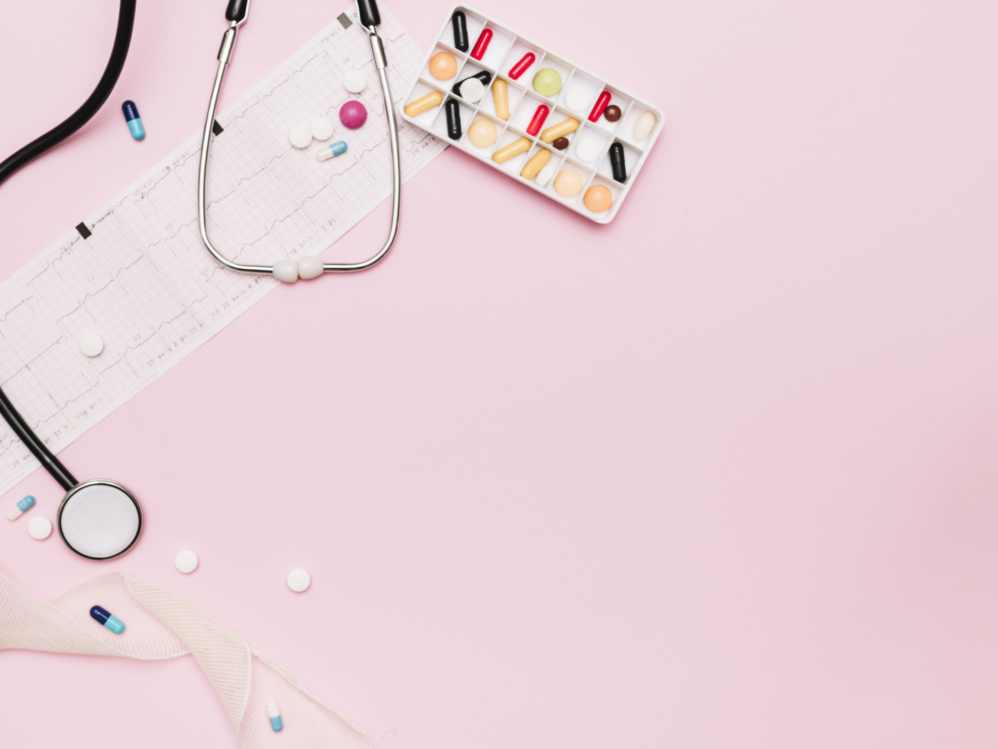 Стетоскоп и лекарства на кардиограмме на розовом фоне