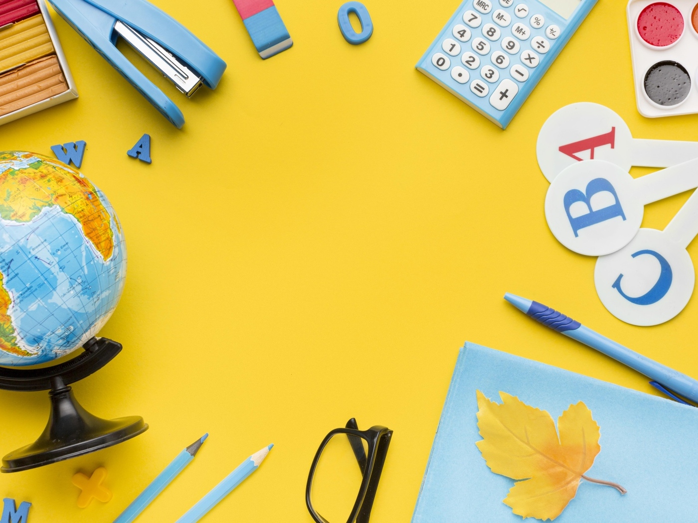 Красивые канцелярские предметы и глобус на желтом фоне