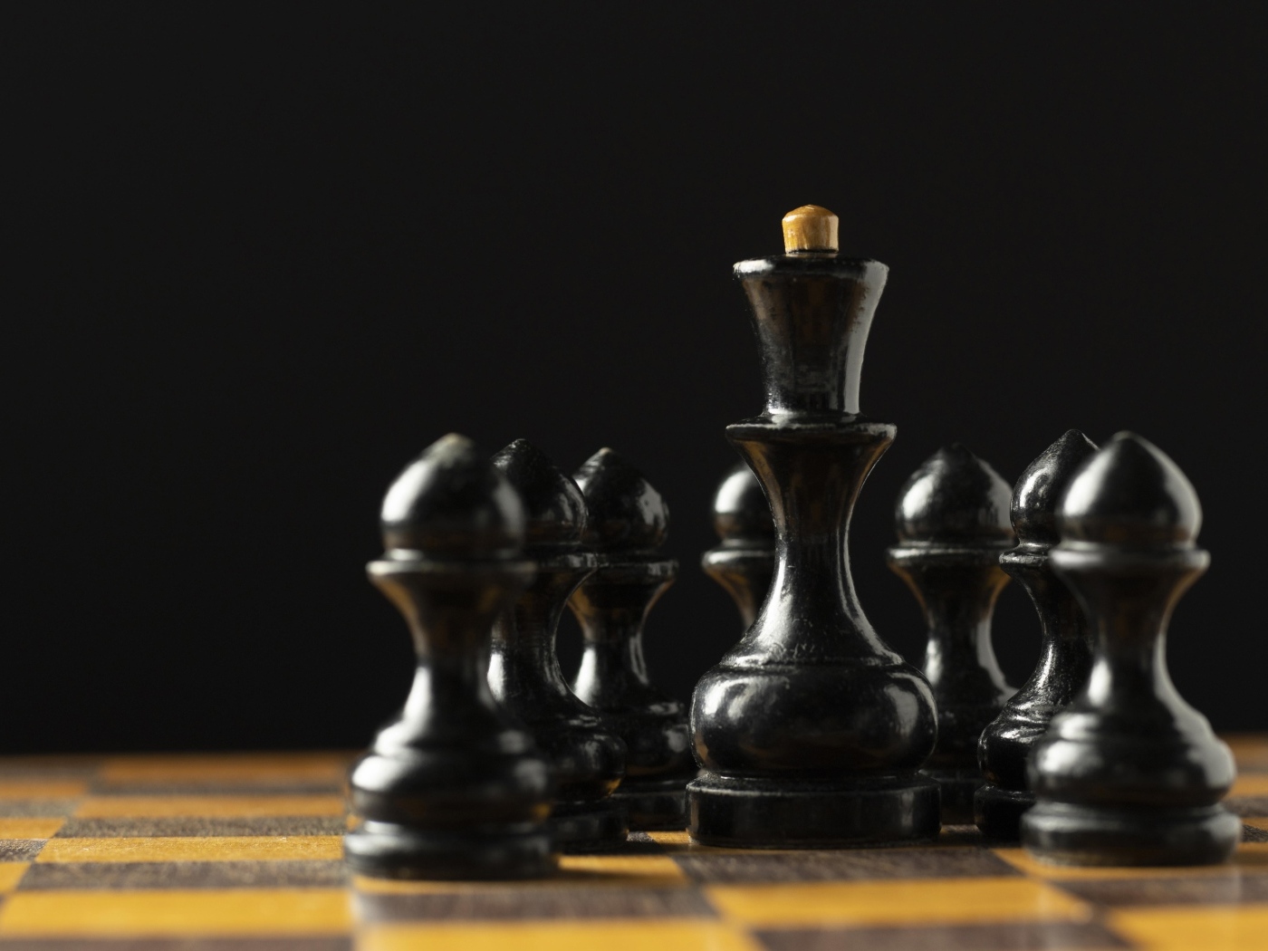 Черные шахматные фигуры на доске на черном фоне