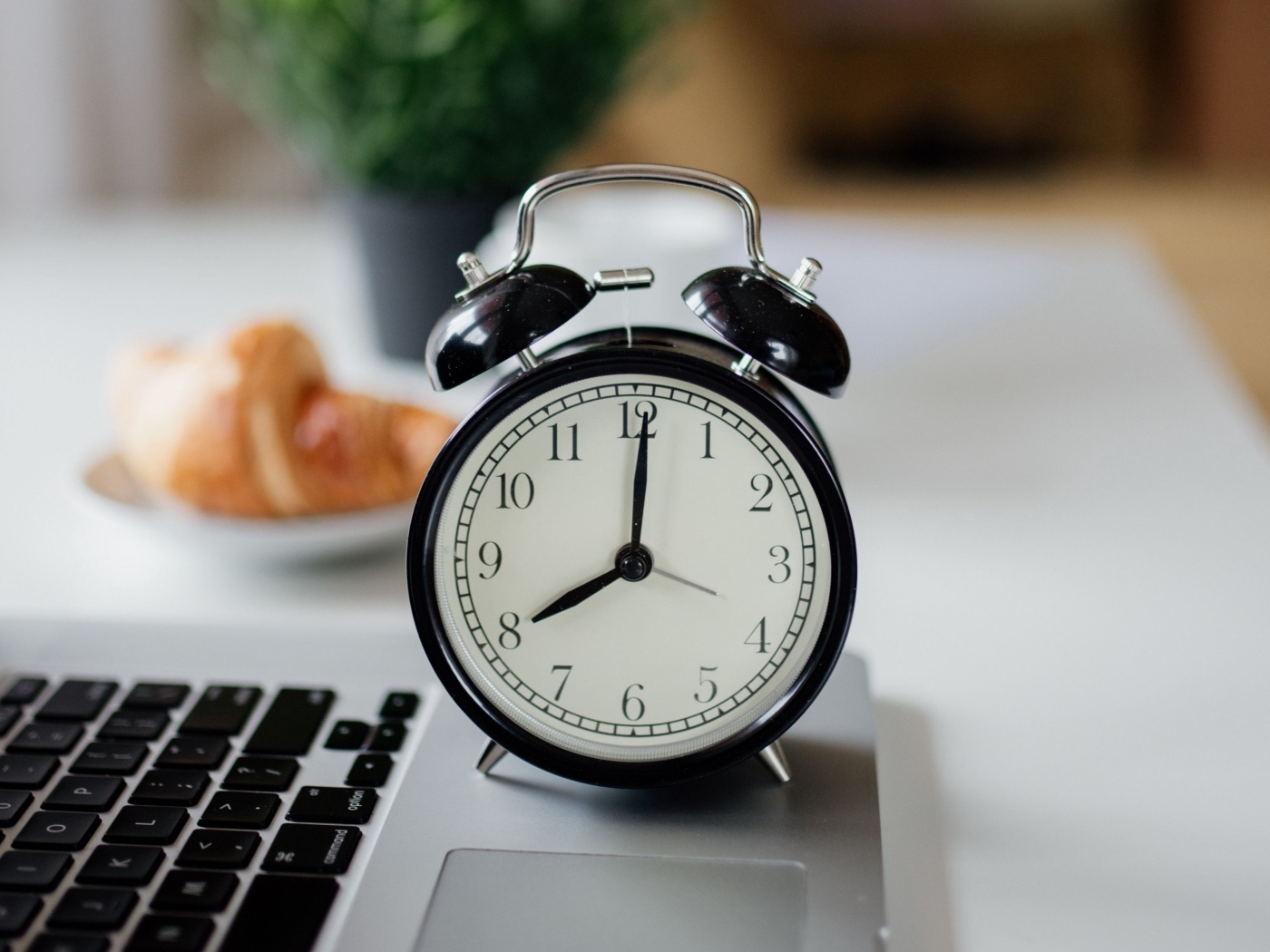 Большой черный будильник на столе у ноутбука