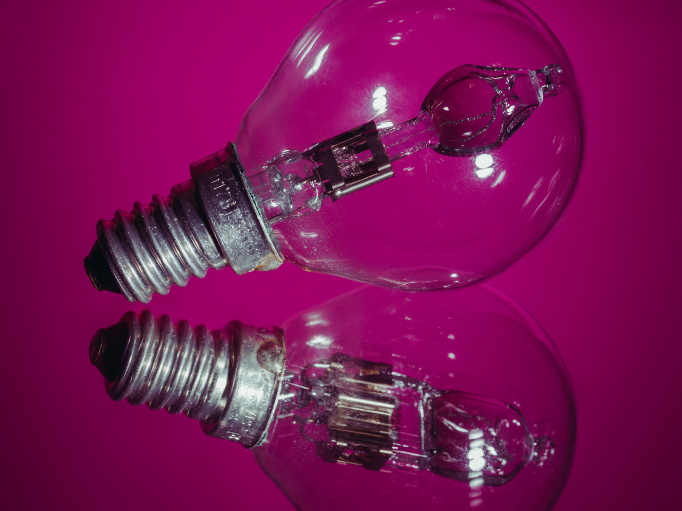 Лампочка отражается в поверхности на сиреневом фоне
