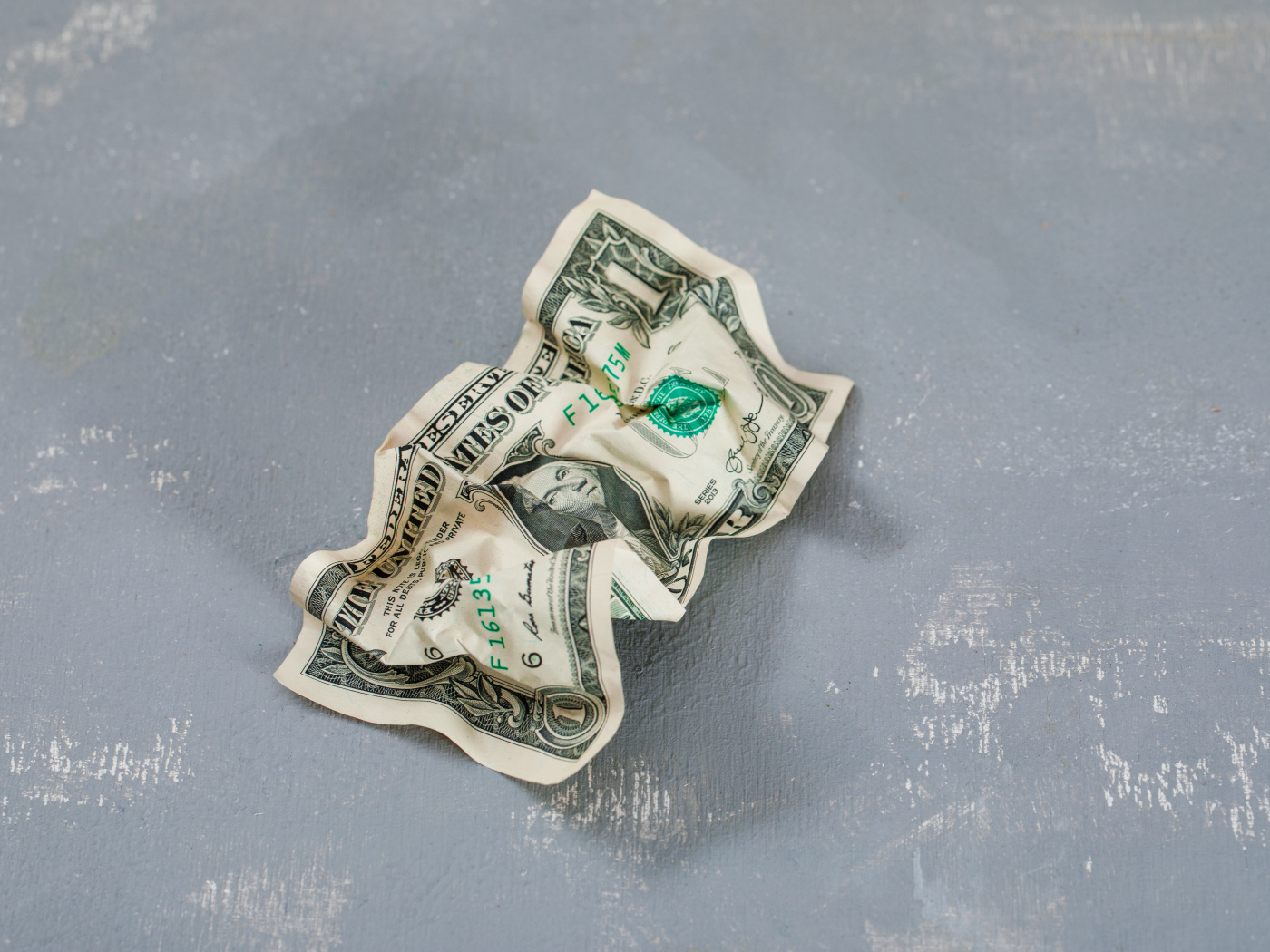Смятая купюра один доллар на сером столе