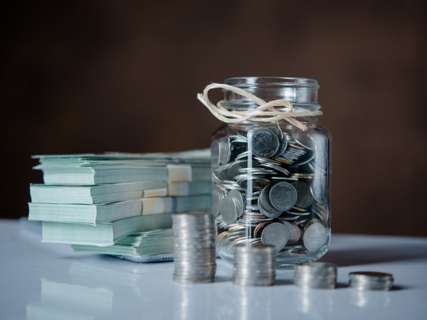 Банка с монетами на столе с пачками денег