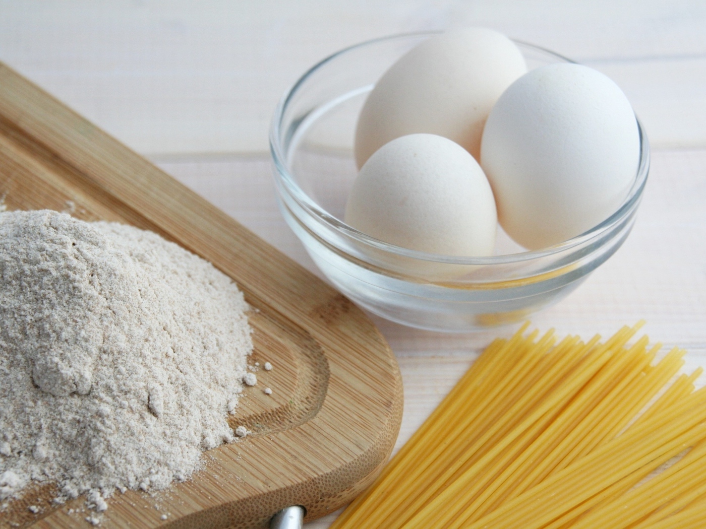 Яйца на столе с мукой и спагетти