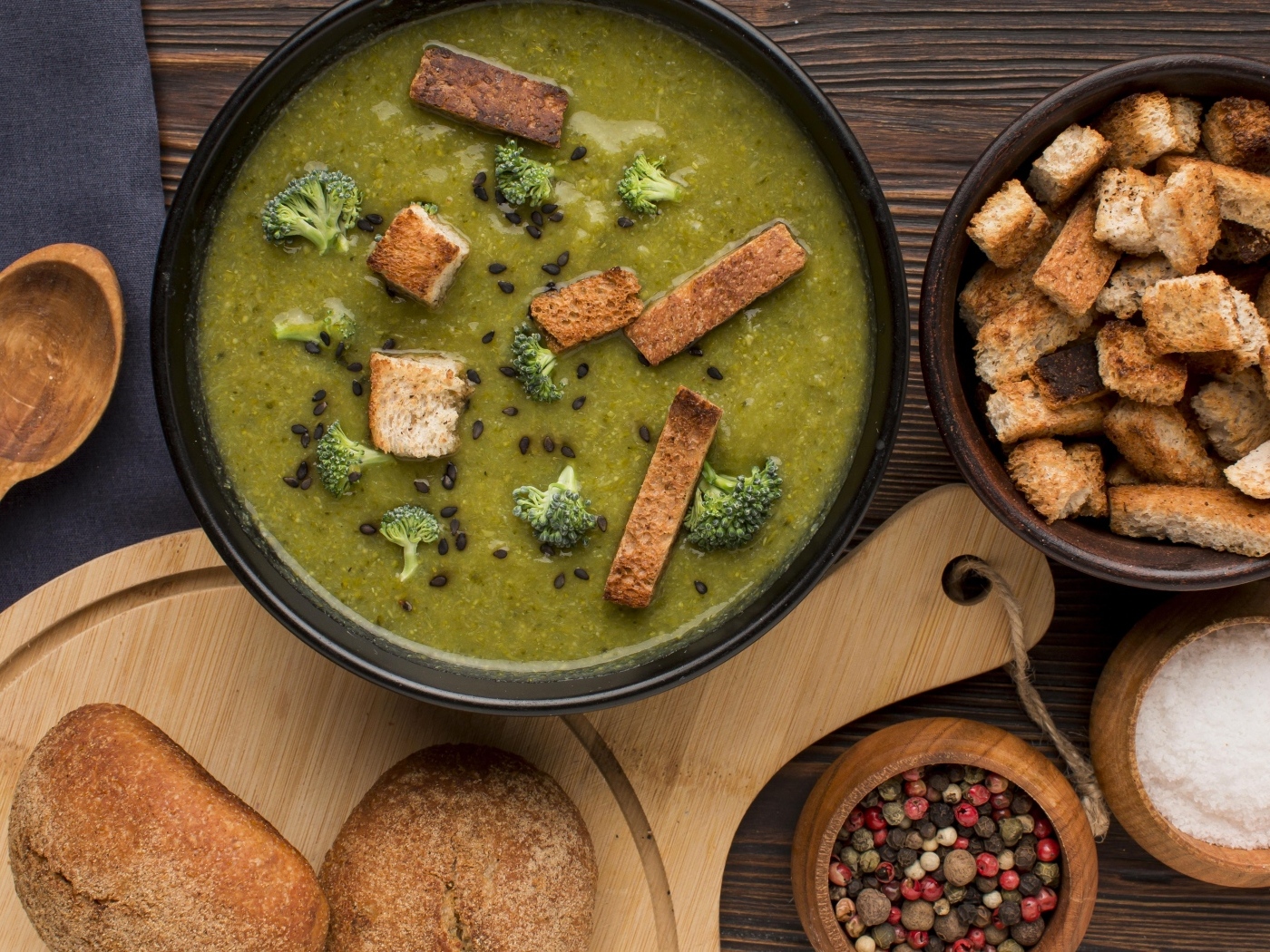 Зеленый суп пюре на столе с сухариками и перцем