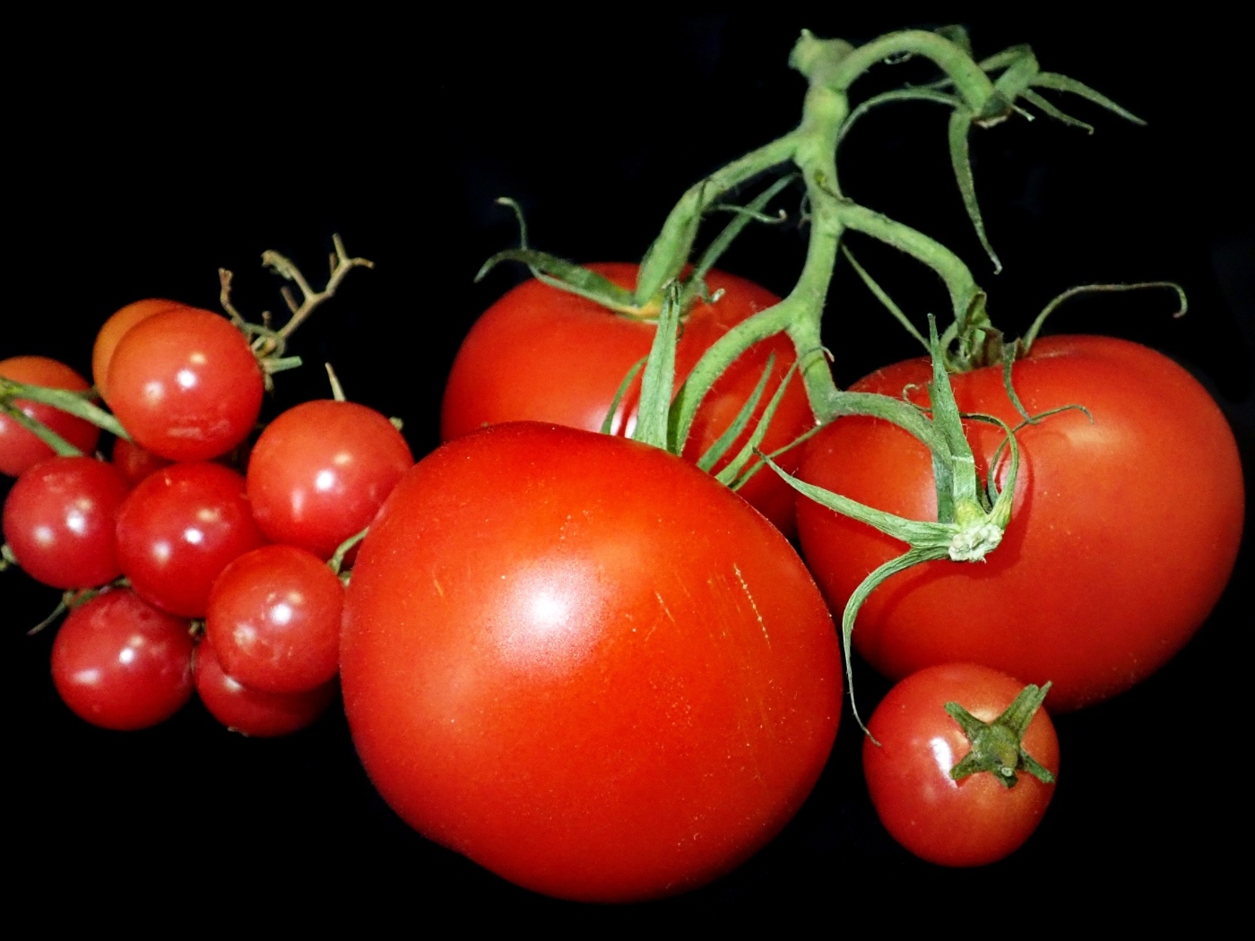 Большие помидоры и помидоры черри на черном фоне