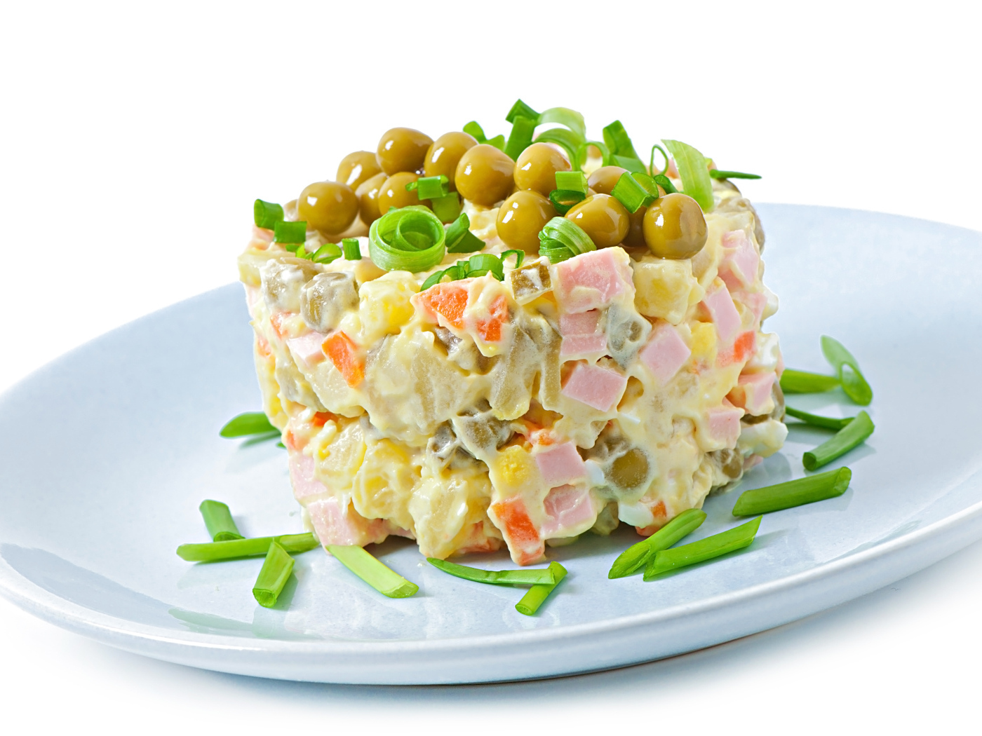 Салат оливье с зеленым горошком на тарелке 