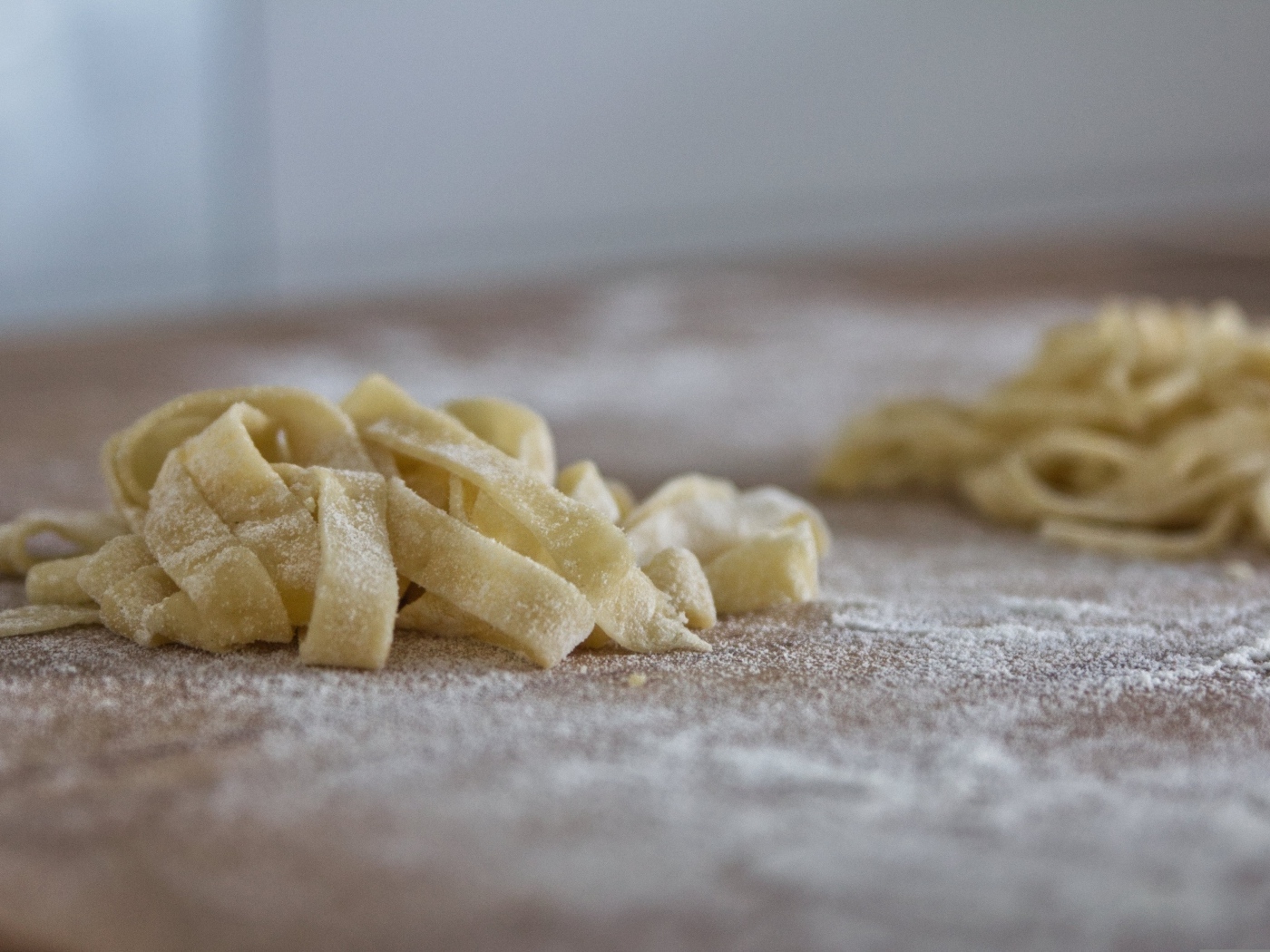 Сырое тесто для лапши на покрытом мукой столе