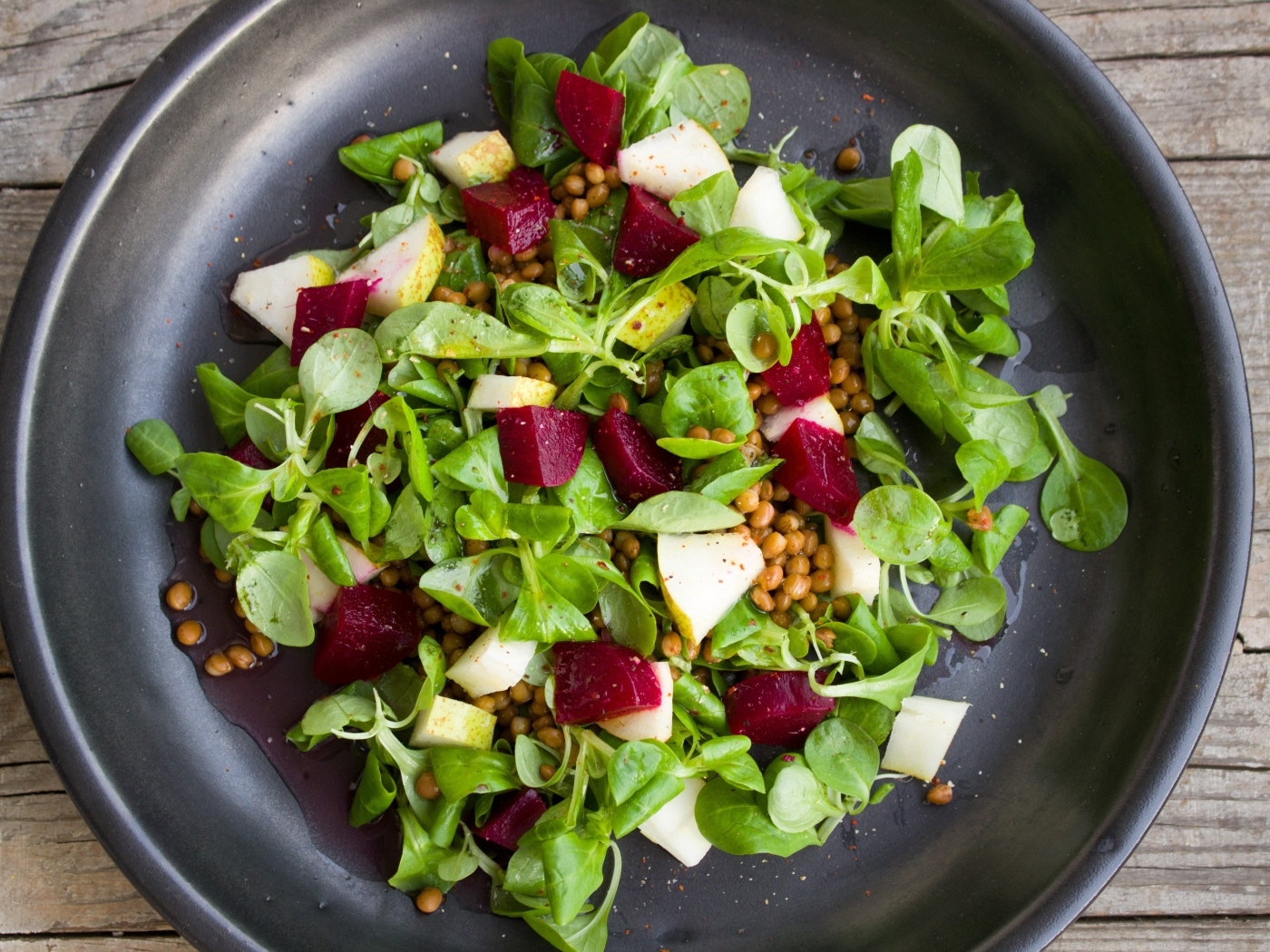 Салат с зеленью в большой черной тарелке