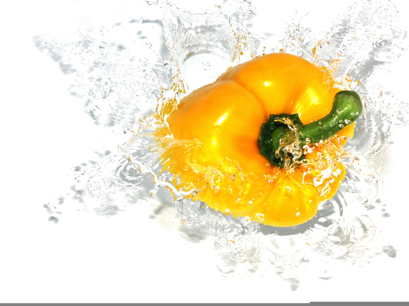 Желтый сладкий перец в воде на белом фоне