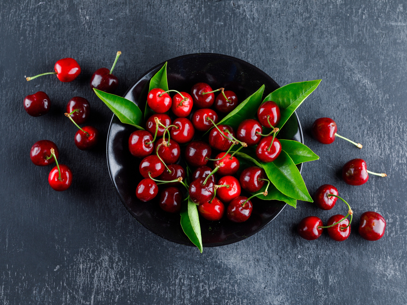 Черная  тарелка с красными ягодами черешни