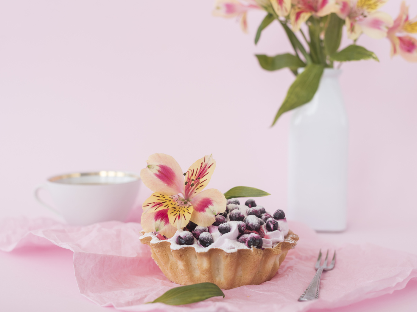 Черничное пирожное с цветами альстромерии на розовом фоне