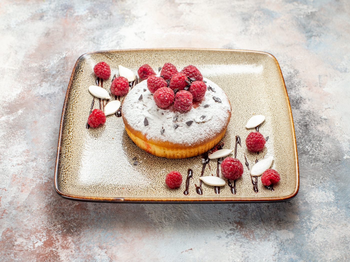 Пирожное с сахарной пудрой и малиной на тарелке