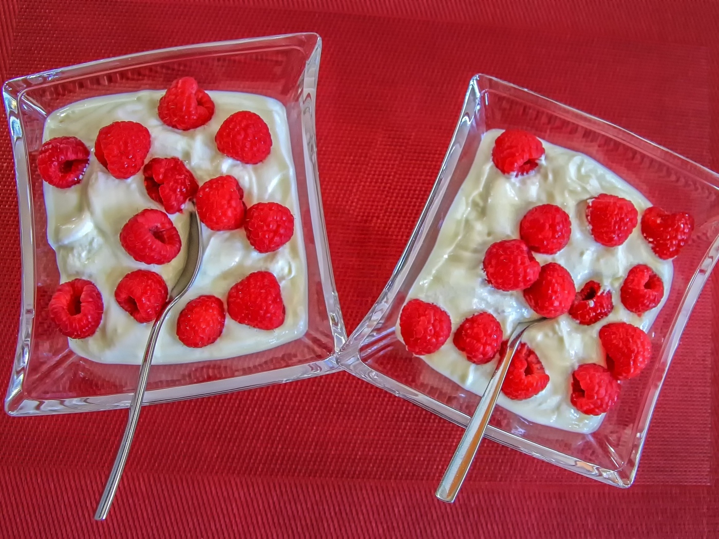 Десерт с ягодами малины на красном столе