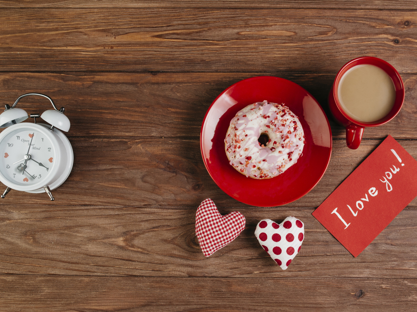 Пончик на столе с будильником, чашкой кофе и сердечками