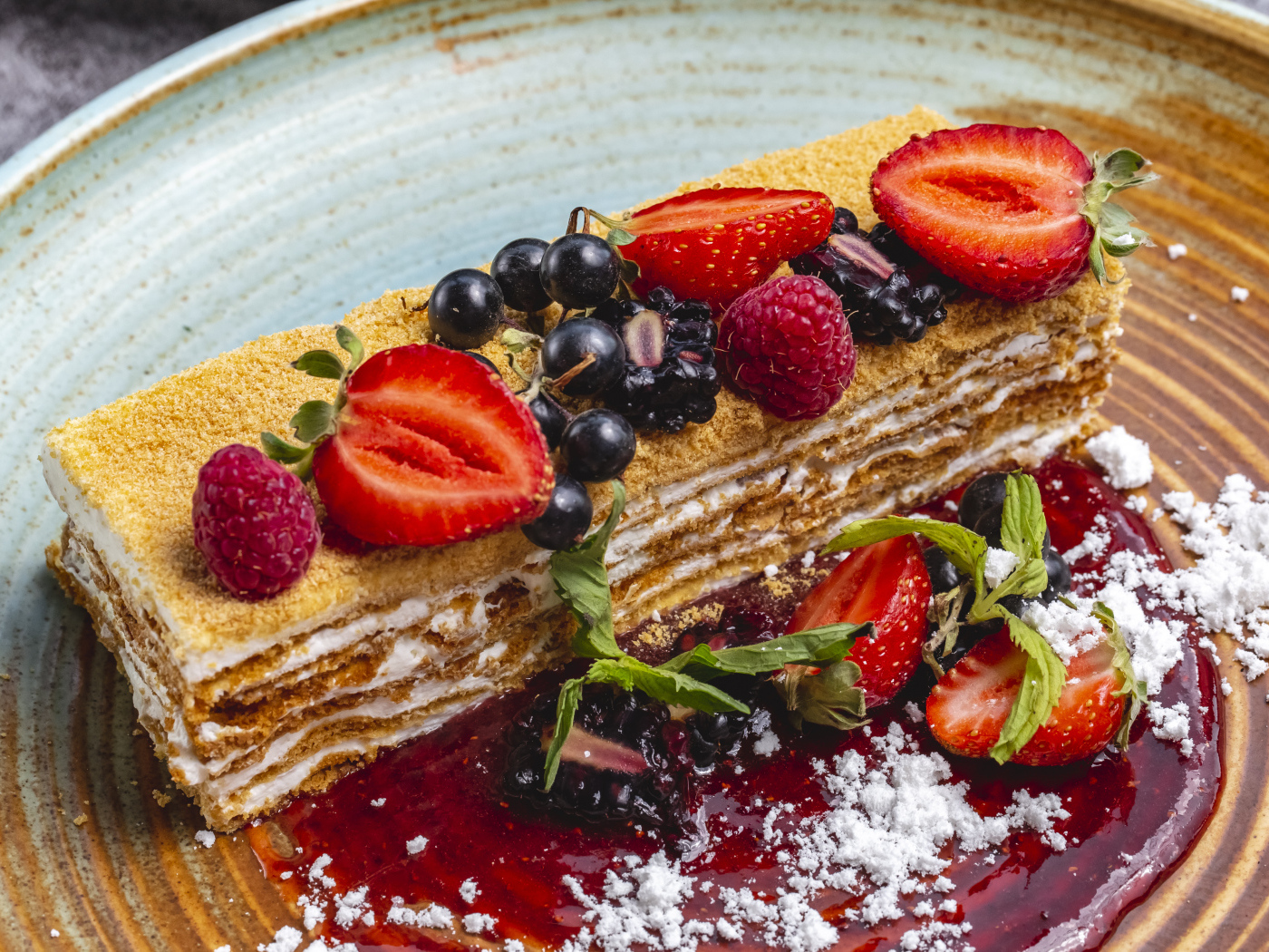 Большой кусок медового торта с ягодами