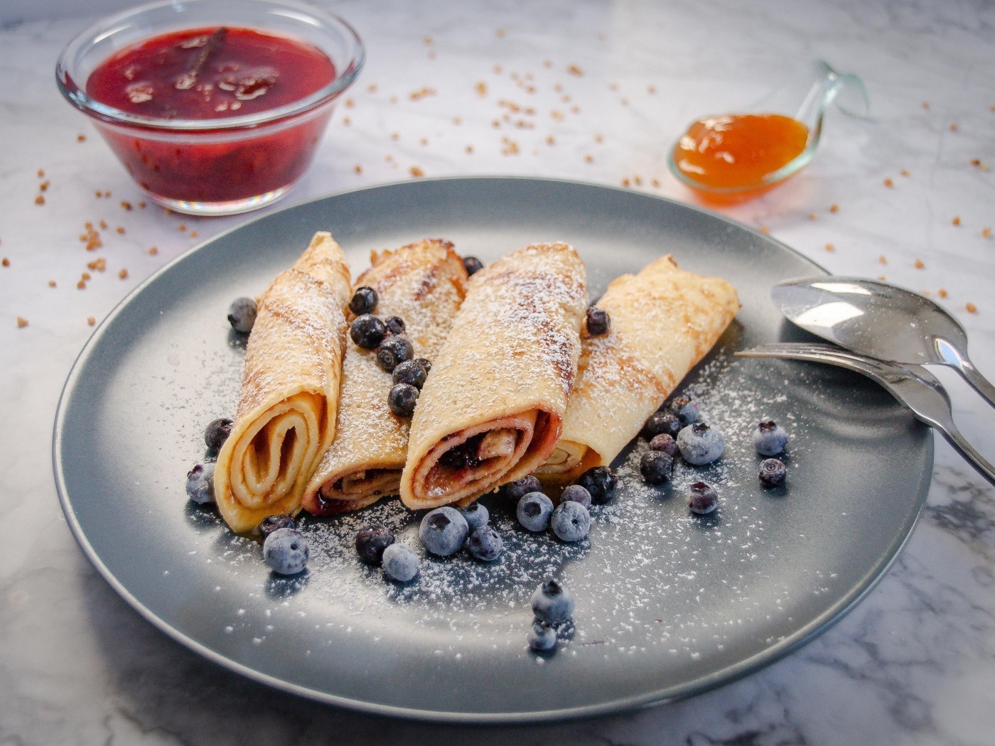 Блинчики с черникой и сахарной пудрой на тарелке на столе