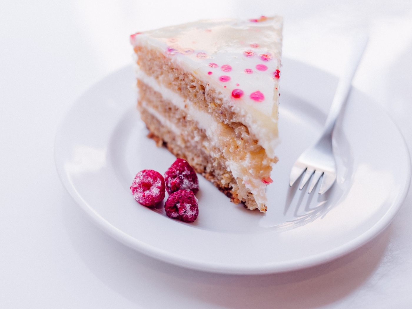 Кусок торта с замороженной малиной на белой тарелке