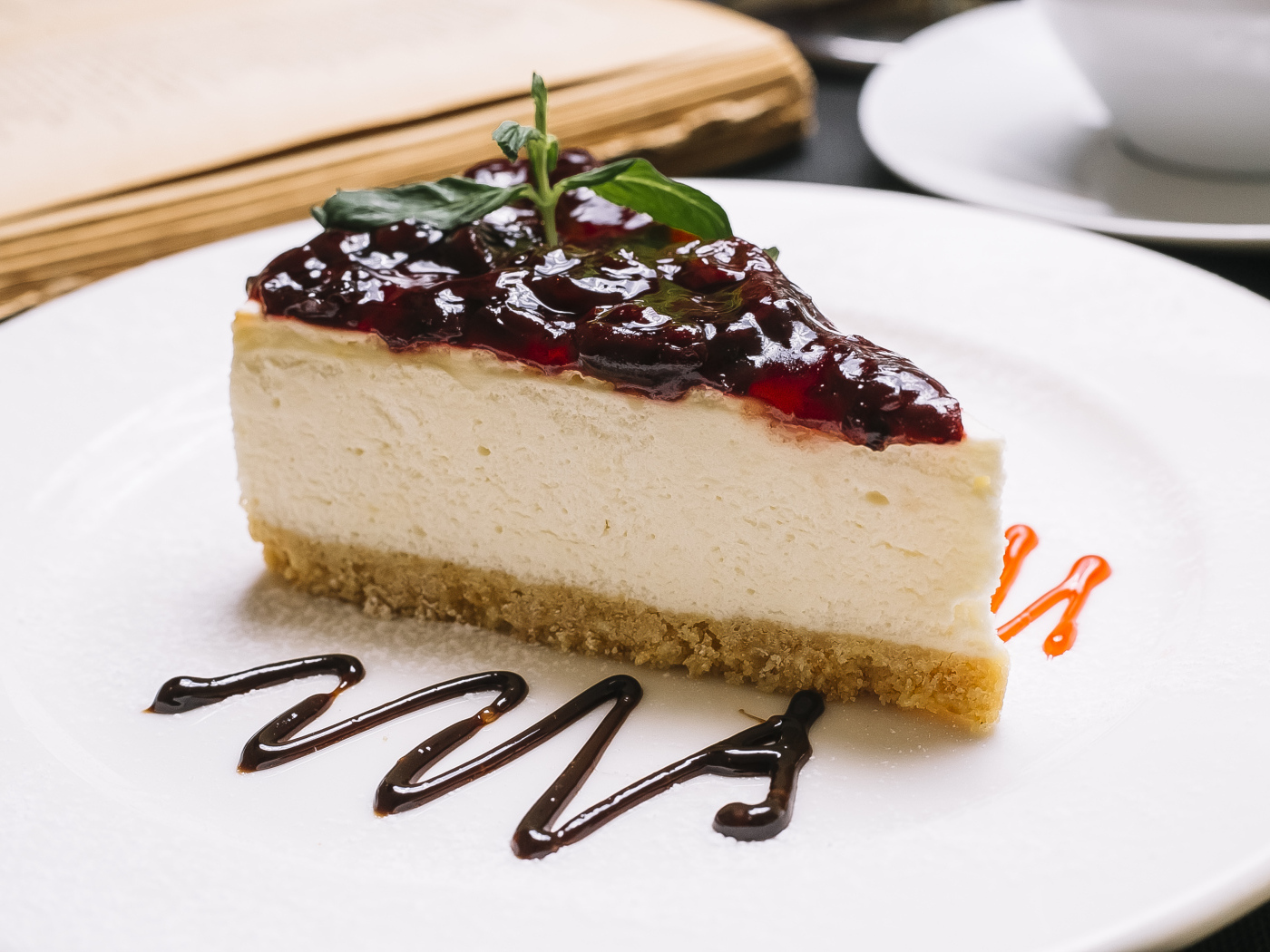 Кусок чизкейка с джемом на белой тарелке