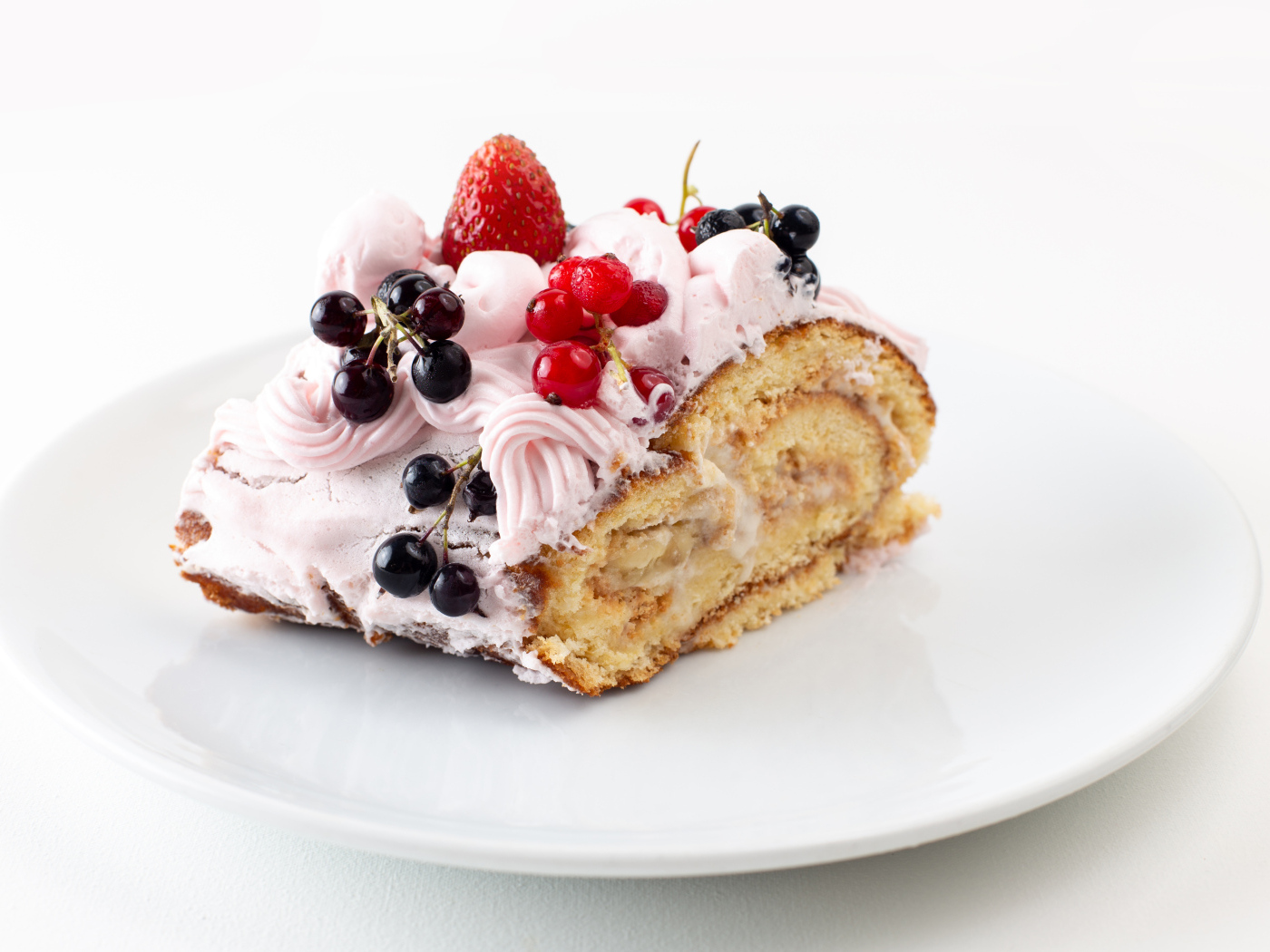 Ломтик сладкого рулета с ягодами и кремом
