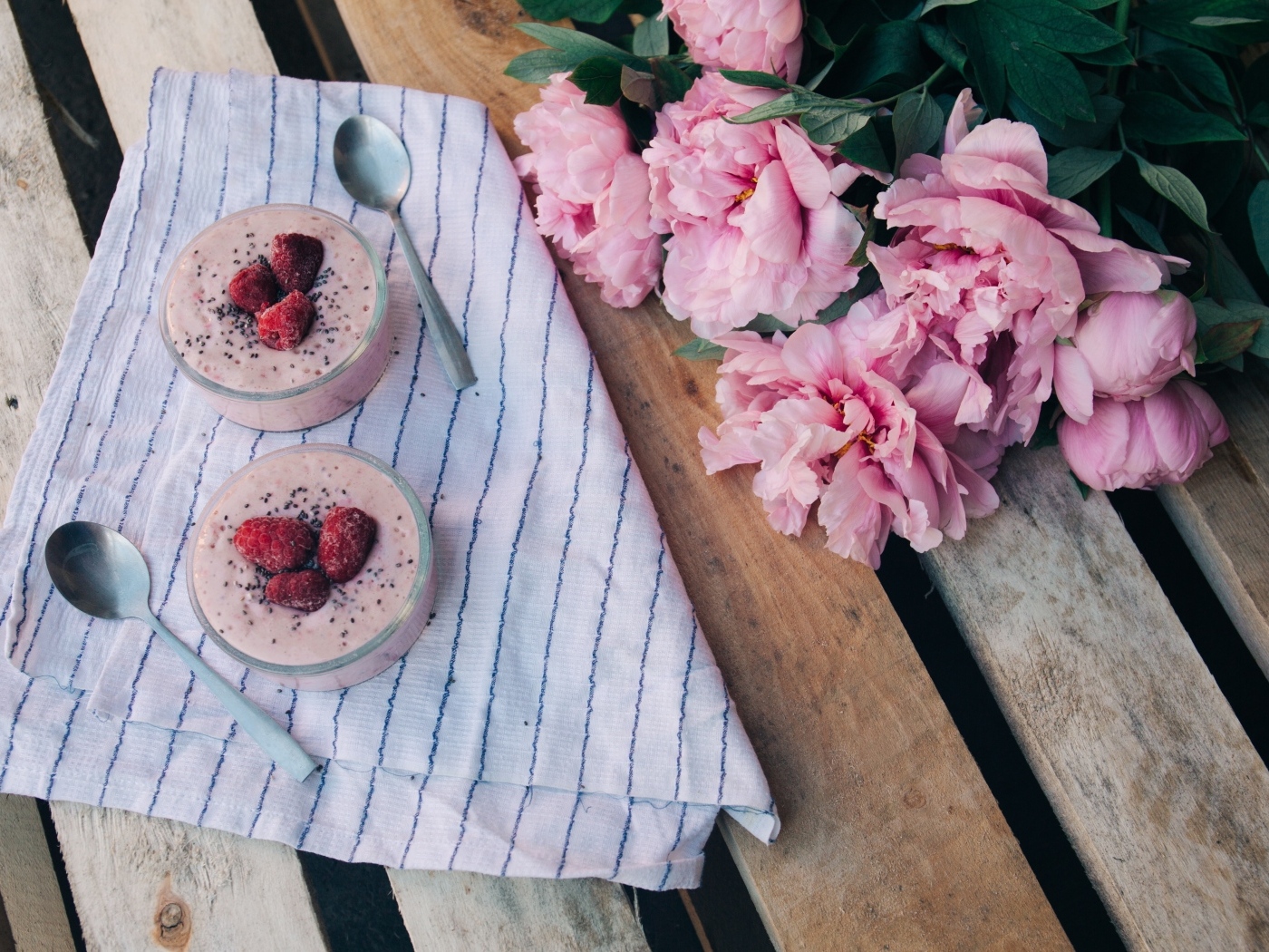 Два стакана с десертом на лавке с букетом пионов