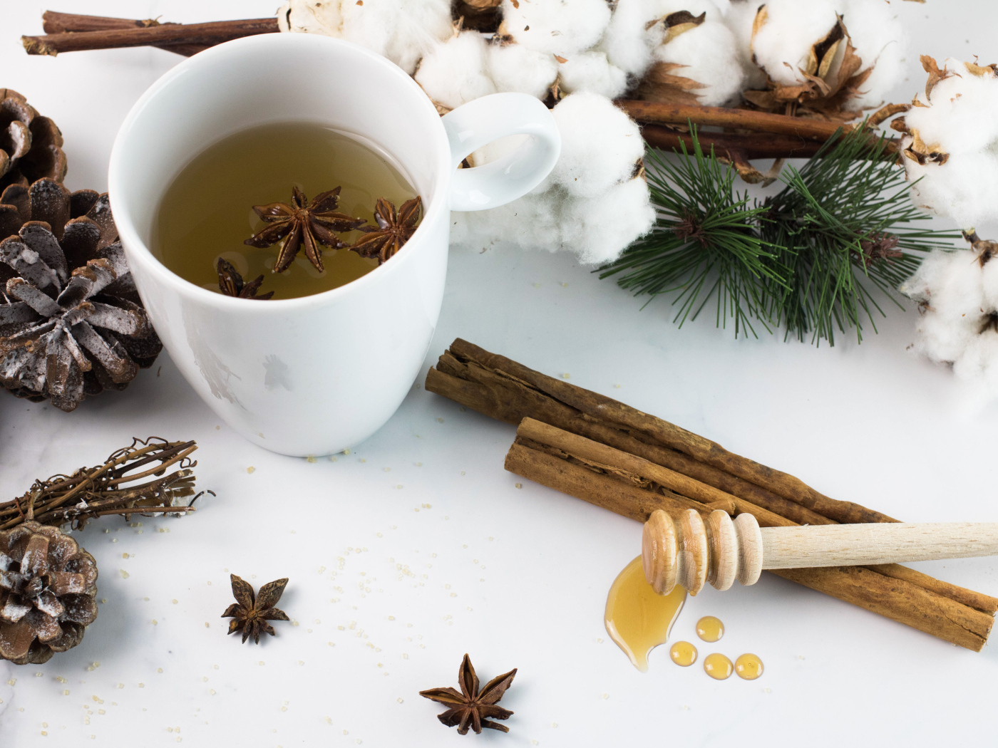 Чашка чая со специями на столе с хлопком и шишками