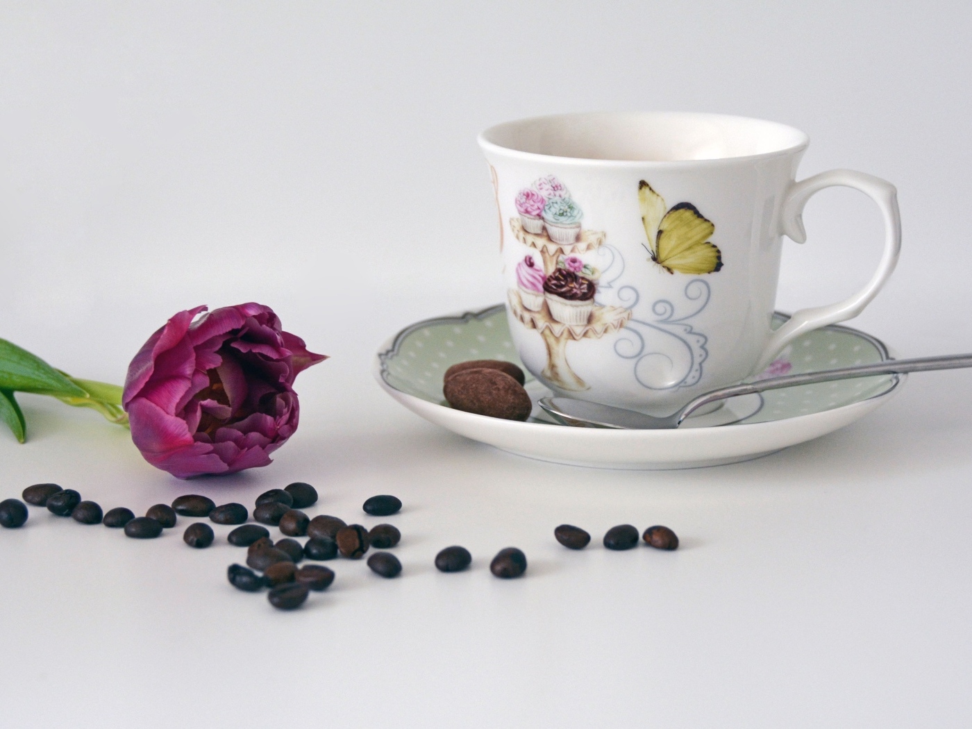 Чашка на столе с кофейными зернами и тюльпаном