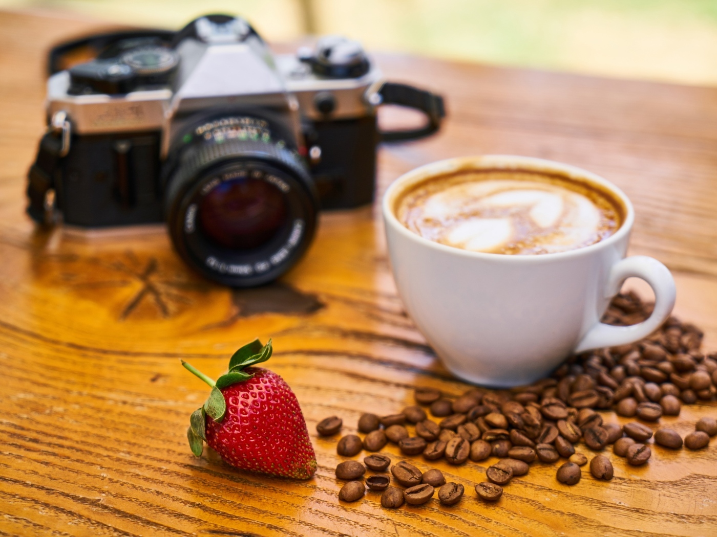 Латте на столе с кофейными зернами и фотоаппаратом
