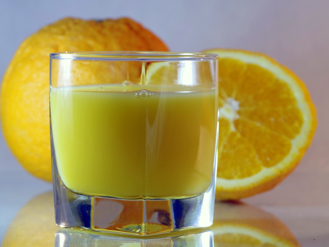 Оранжевый апельсиновый сок в стакане на столе с плодами
