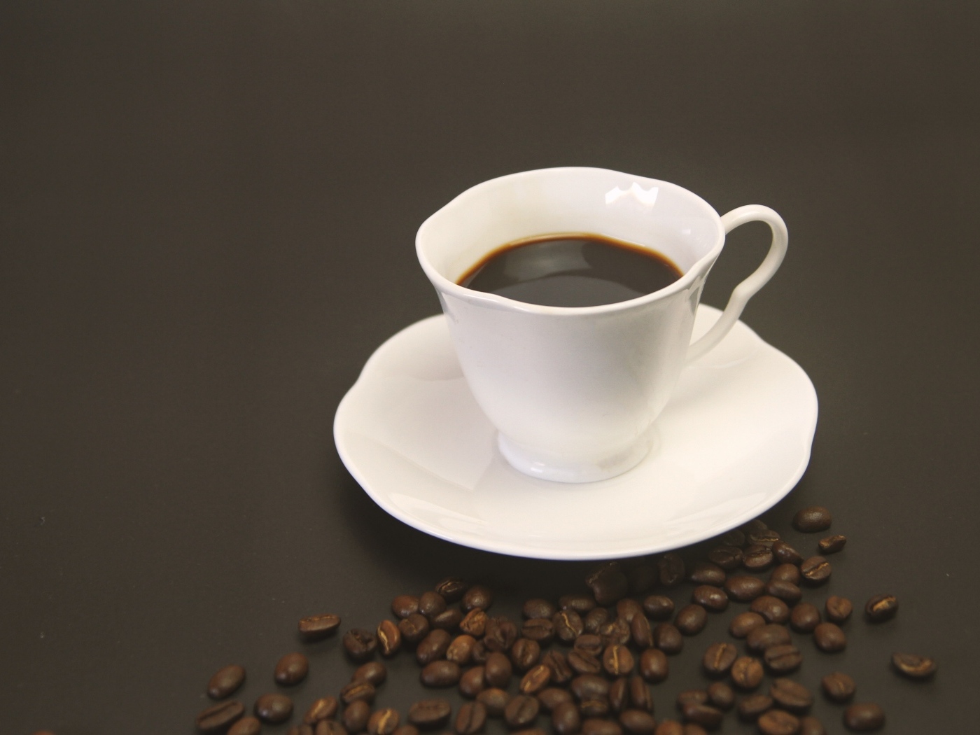Белая чашка с кофе на столе с зернами