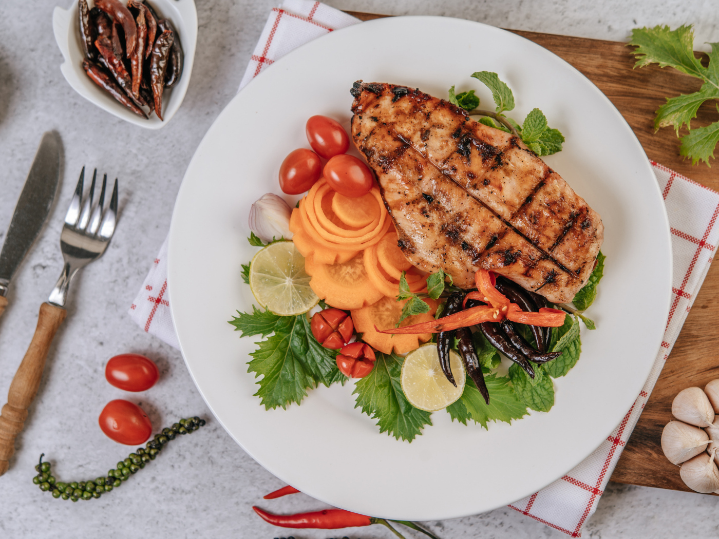 Кусок жареной курицы на большой белой тарелке с овощами