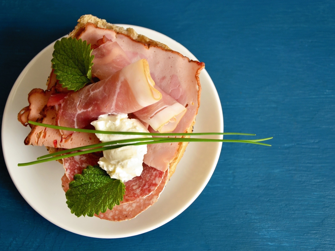 Бутерброд с колбасой и беконом на синем столе